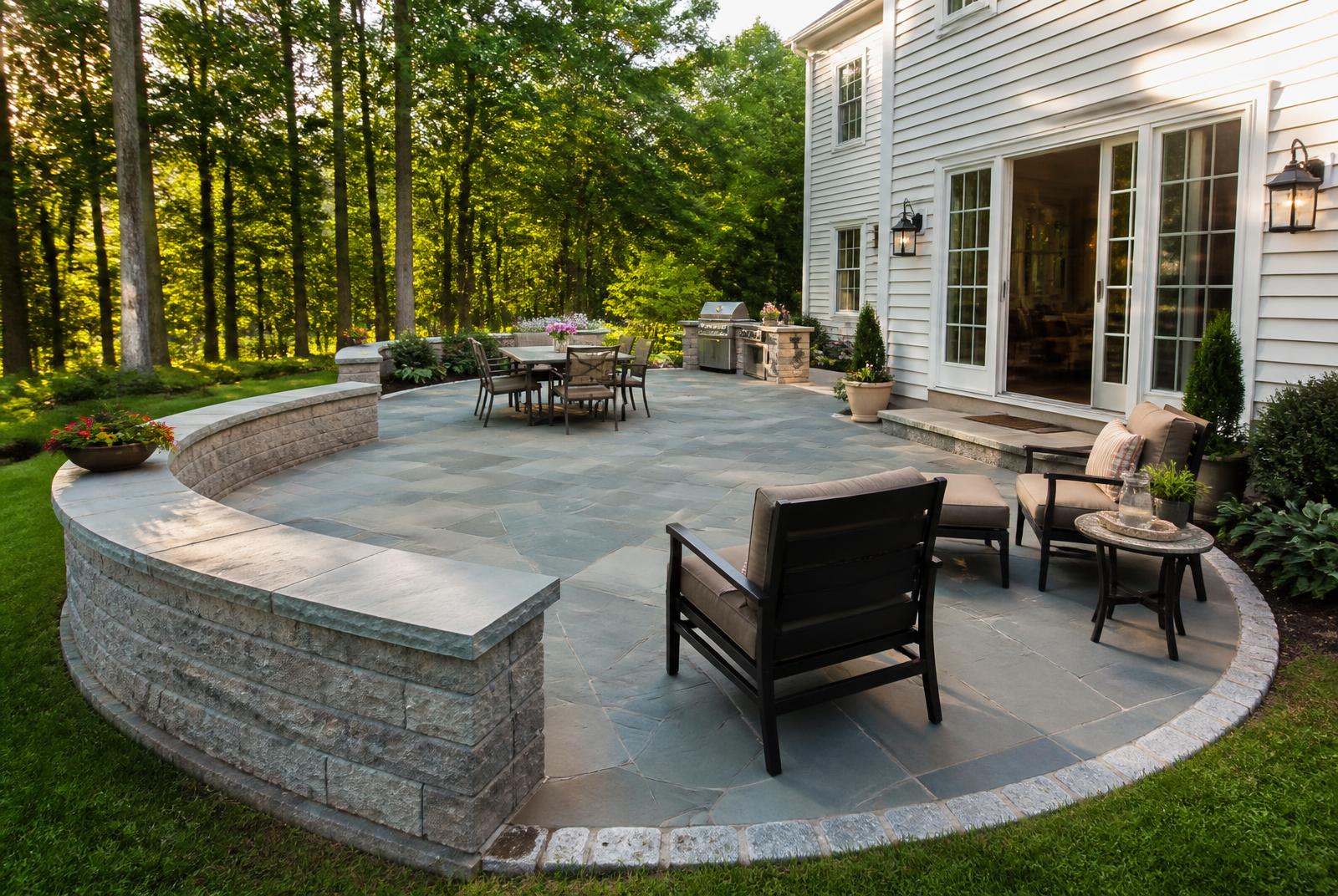 Large bluestone patio with curved seat walls behind a Windham, NH colonial